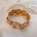 Minimalistisches goldfarbenes Armband mit Hammerschlag-Design auf weißem Satin-Stoff - Gold