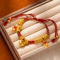 Detailed shot of a red woven rope bracelet with gold persimmon and Ruyi pendants - L269-4 Persimmon Ruyi