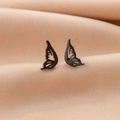 Detail view of butterfly wing earrings with black matte finish on beige silk fabric - Black Bat Wings