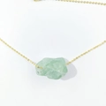 Detailed view of irregular green crystal pendant on a delicate gold chain necklace - Fluorite