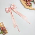 Close-up of soft pink satin bow hair clip with long ribbons on a decorative gold tray - Orange Pink