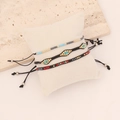 Close-up of three handmade bohemian woven seed bead bracelets on a white pillow display - Black