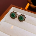 Primo piano di orecchini a fiore vintage con pietra verde e base in metallo dorato - Stile Sole Tondo / Orecchini ad Ago in Argento-Verde