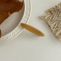 Dettaglio macro di un fermaglio per capelli ambra con logo France Handmade su vassoio - Caffè Caramello