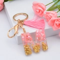 Pink resin letter M keychain with gold foil flakes and matching pink tassel on white background - M