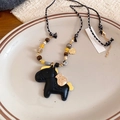 Detailed shot of the black pony pendant with yellow wing on a beaded leather necklace - Black Leather Yellow Wing Pegasus Necklace