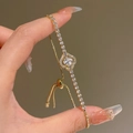 Close-up of golden four-leaf clover bracelet with zircon stones and adjustable drawcord - Gold