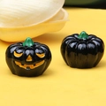 Detailed macro view of two mini black Halloween pumpkin ornaments with a yellow smile face - Non-Luminous Black Pumpkin Orange Eyes