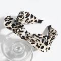 Detailed view of leopard print bow headband on clear glass display with white background - Large Leopard Beige