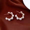 Détail de boucles d'oreilles C plaquées or avec perles sur fond en soie rouge - Tige en argent 925 / Blanc perle
