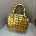 Goldene geflochtene Mini-Handtasche mit Knotenanhänger auf beigem Hintergrund - Gold