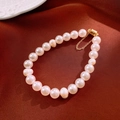 Gros plan d'un bracelet en perles d'eau douce avec fermoir magnétique doré chic - Blanc