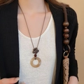Close-up of translucent amber resin ring pendant necklace with vintage knot detail - Round Style