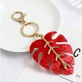 Detail showing red resin leaf keychain with gold metal veins and lobster clasp - Red Pearlescent Monstera Leaf / Red