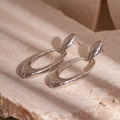 Macro shot of silver geometric oval earrings resting on a textured stone surface - Silver Oval Stud Earrings / Silver
