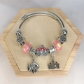 Detail of steel cable bracelet with pink beads, elephant and crown charms on wood - Red