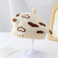 Gros plan détaillé du béret en tricot avec motifs de cœurs bruns et écusson couronne - 50-52cm (2-4 ans) / Beige