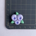Size measurement of a purple resin blueberry charm with green leaves on a ruler mat - Purple Blueberry