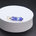 Blue crystal hexagonal pendant with gold wire wrap on white pedestal display - Watermelon Blue Glass