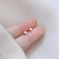 Macro view of 925 sterling silver star stud earrings on a fingertip for scale - Small Stars / Silver
