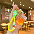 Detail of orange liquid quicksand drink keychain with yellow strap and bell charms - Strawberry Strap Orange Luminous Dried Flower Iceberg Cup