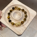 Detailed close-up of tiger eye stone beads and hollow gold flower charm on wooden tray - Zircon Character Cylinder Tiger Eye Style