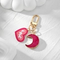 Detail of pink resin heart and moon charms with golden edges on a metal keychain - Moon + Heart