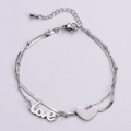 Dettaglio di un bracciale a doppio strato argento con ciondolo a cuore e pendente inciso - Color Acciaio
