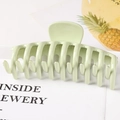 Detail of a large pale green claw hair clip featuring a geometric split bone structure - Glossy Green