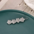 Silver hair clip with four rhinestone flower clusters on a decorative green ceramic plate - Silver Rhinestone Style (B6503)