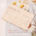 Close-up of white pearl necklace with pink heart pendant on stone and floral magazine - White