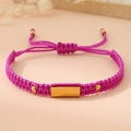 Macro shot of rose pink woven rope bracelet with gold metal plate and adjustable knot - Purple (Gold Plate)