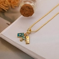 Gouden kralenketting met vliegtuig, paspoort en koffer bedeltjes op een boek - Vliegtuig Paspoort Koffer Stijl