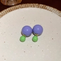 Close-up of purple and green double ball stud earrings on a beige ceramic tray - Purple and Green Double Ball Style