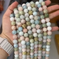 Hand holding colorful Morganite and Beryl round gemstone beads in pastel shades - Single Strand Price / Grade A 12mm (Approx 30 Beads/Strand)
