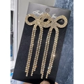 Gold bow earrings with sparkling rhinestone tassels on a black jewelry card - Stud Earrings / Gold White Zirconia