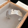 Dettaglio del bracciale aperto argento con texture lavica in scatola di legno - Stile Aperto con Trama Lavica Martellata / Argento