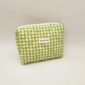 Close-up of green and white quilted corduroy makeup bag with a stitched woven label - Green and White Plaid