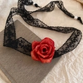 Detalle de una gargantilla de encaje negro con una rosa roja metálica sobre un libro gris - Collar de encaje negro rosa roja / Negro Rojo