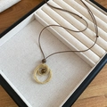 Détail du pendentif en pierre œil de tigre avec anneaux dorés sur plateau à bijoux noir - Style Rond / Doré