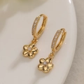 Minimalistische vergoldete Blumen-Creolen mit Zirkonia-Steinen auf einem weißen Teller - Blume / Gold