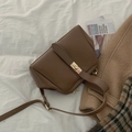 Vintage brown leather crossbody bag with golden metal twist lock on a textured background - Brown