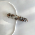 Macro shot of rectangular marble hair clip with amber floral details on ceramic tray - Marble Gray