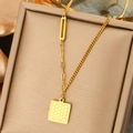 Dettaglio macro della collana in titanio dorato con perla e ciondolo quadrato moderno - Catena Asimmetrica Minimalista
