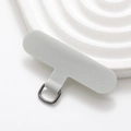 Macro shot of grey fabric phone tether tab with durable metal D-ring on white tray - Light Gray