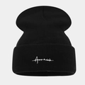 Detailed view of the soft knit texture and white script embroidery on this black beanie - Black