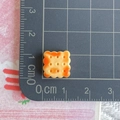 Macro shot of 1cm resin bread biscuit miniature on a ruler for size reference - Square Scalloped Cookie