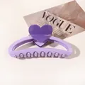 Close-up of a purple heart claw clip with large teeth for thick hair over a magazine - Heart Hollow Semicircle / Light Purple