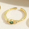 Macro shot of gold adjustable ring featuring oval green gemstone and clear side stones - Adjustable Open / Emerald Oval Zirconia Style (JZ0333)