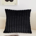 Plush black square throw pillow with vertical striped texture on a cozy white sofa - Black